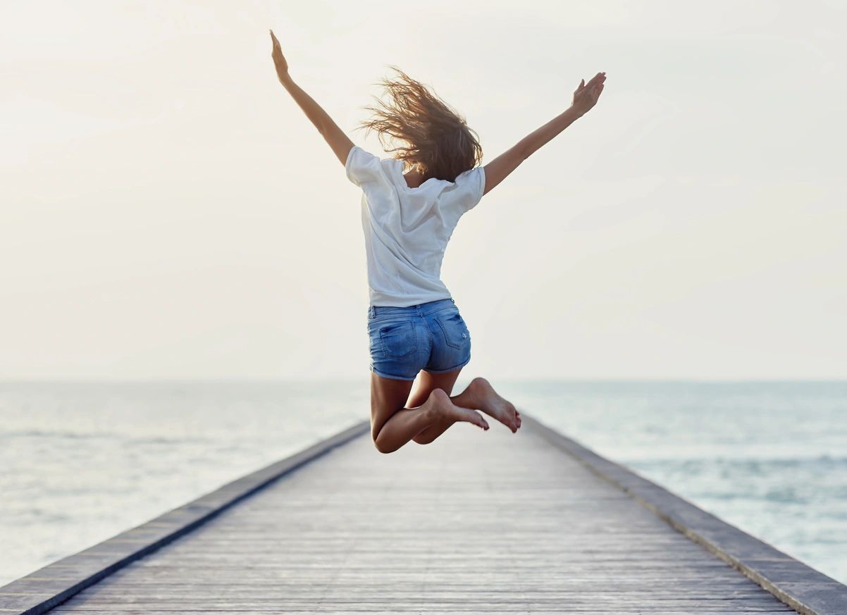 Person jumping joyfully on a pier
